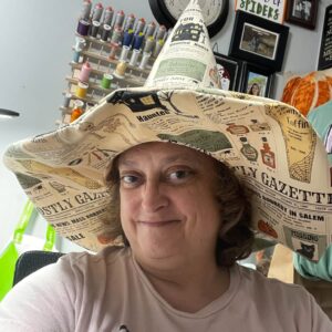 Handmade witch hat in Ghostly Gazette Halloween newsprint fabric, worn by the maker